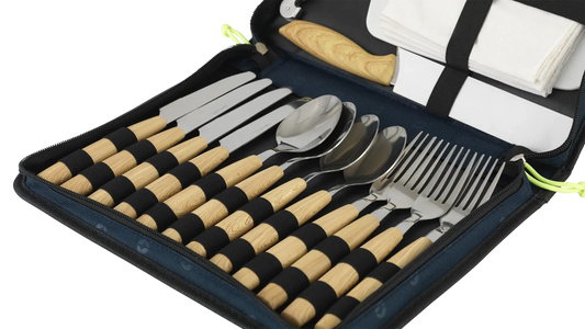 Outwell Morella picnic cutlery set with stainless steel knives, forks, and spoons arranged on a wooden table for outdoor dining.