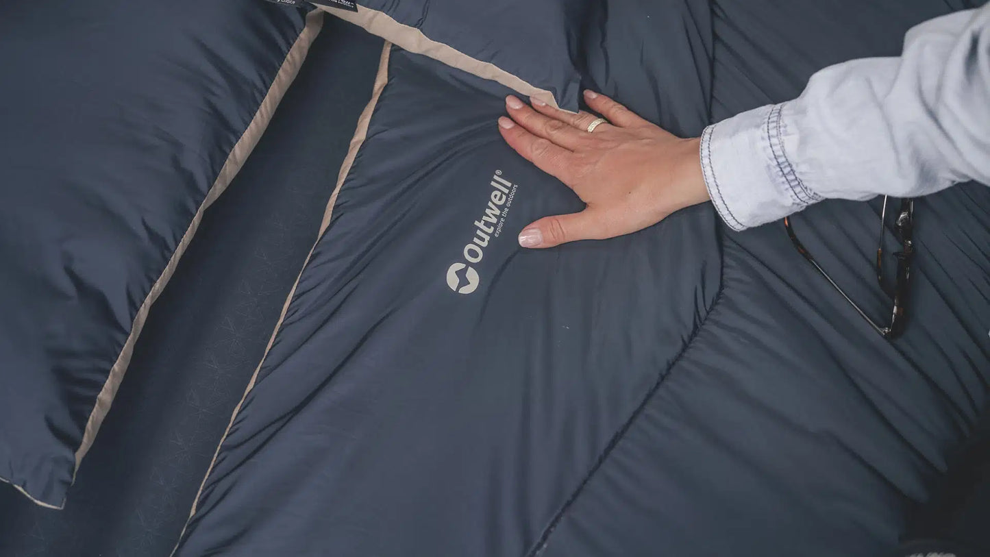 Outwell Caldera Double Blue duvet laid out on a bed, showcasing its soft fabric and cozy appearance for comfortable sleeping.
